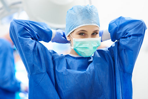 Young female surgeon tying her surgical mask