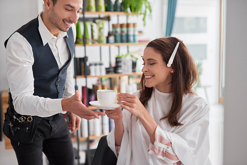 Beautiful woman drinking coffee in hair salon