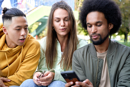 Close up of three young people with mobile phone outdoors