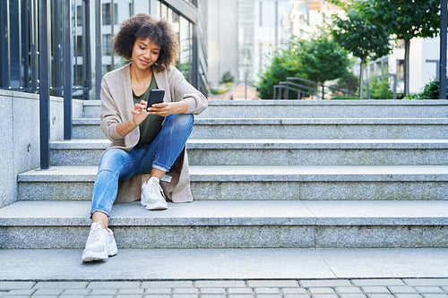 Woman sitting on city steps and using on the phone