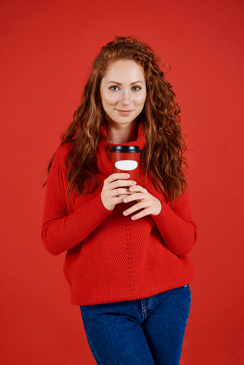 Portrait of beautiful girl holding disposable mug of coffee