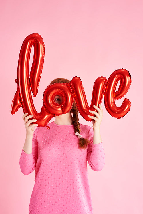 Young woman covering her face with balloon at studio shot