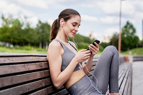 Athletic woman sitting and listening to music on the phone