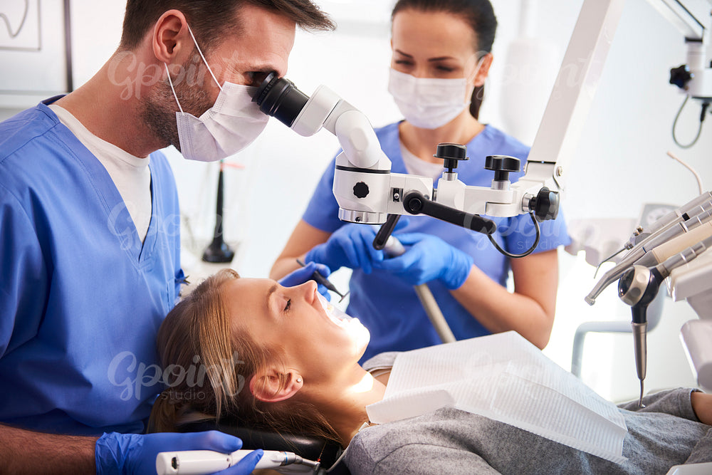 Male dentist working with dental microscope