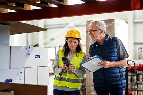 Two caucasian workers in mature age discussing together in warehouse