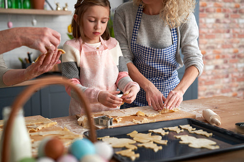 Little girl making Easter cookies with family at home