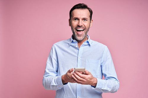 Smiling man holding mobile phone in hands