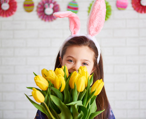 Smiling woman in rabbit costume holding a bunch of tulips
