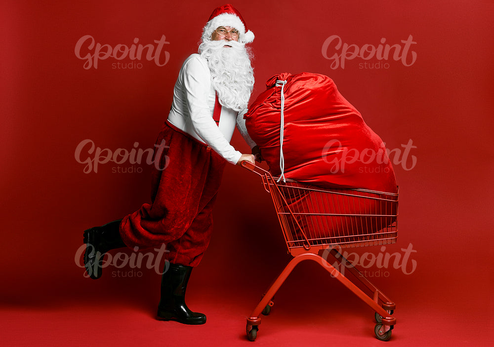 Caucasian Santa Claus pulling shopping cart full of Christmas's presents