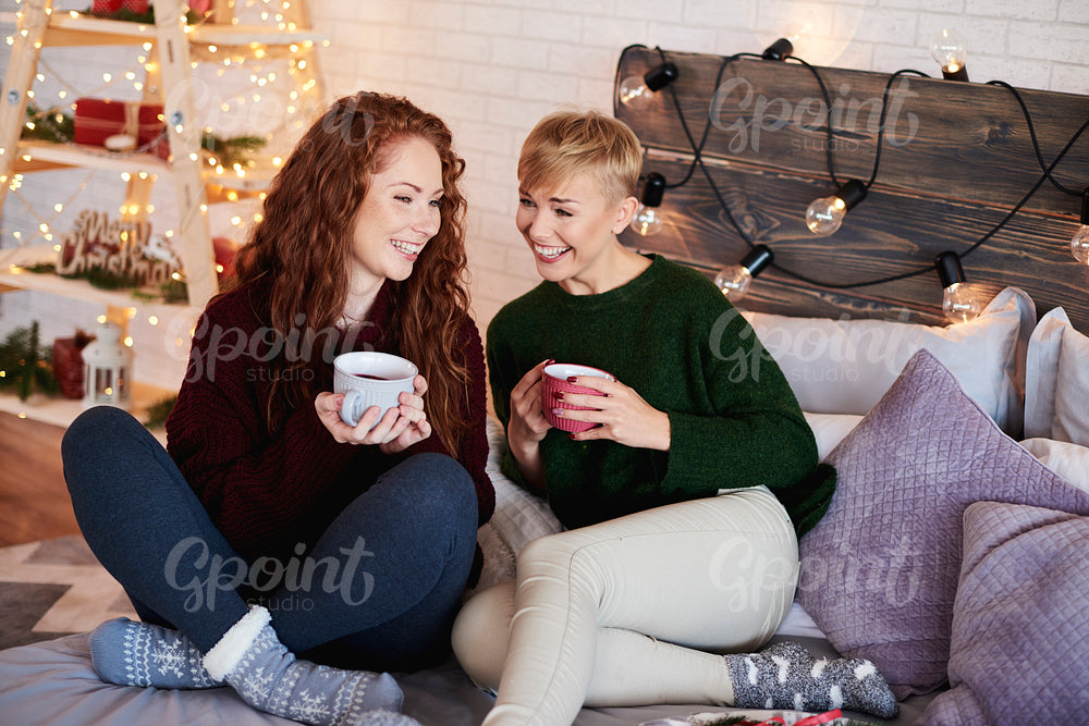 Friends drinking tea and talking at bedroom