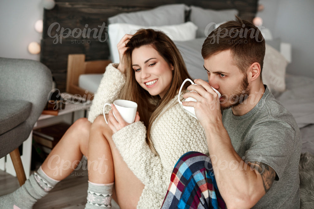 Affectionate couple drinking morning coffee at bedroom