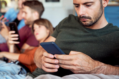 Man focused on smart phone at party