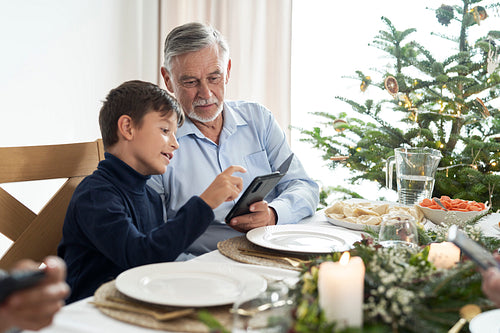 Grandson showing his grandfather how to use smartphone over Christmas table
