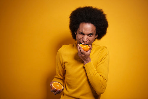 Afroamerican biting into a juicy orange