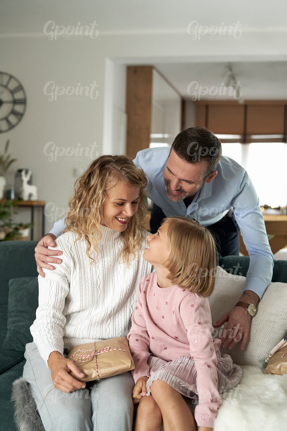 Vertical image of  caucasian family of parents and girl sitting and holding Christmas presents