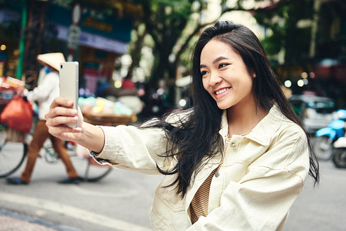 Young Vietnamese woman taking a selfie on the street
