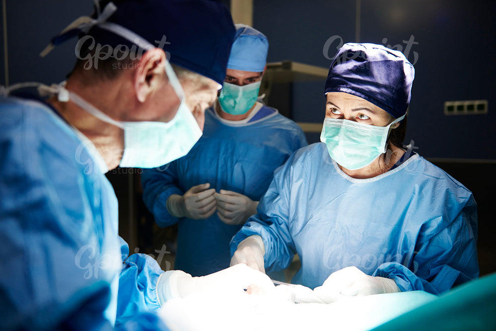 Team of surgeons working together during operation in darkness