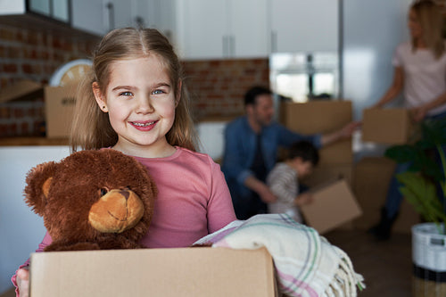 Portrait of little girl holding cardboard box with teddy bear