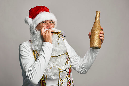Caucasian Santa Claus celebrating with glass of champagne and party blower