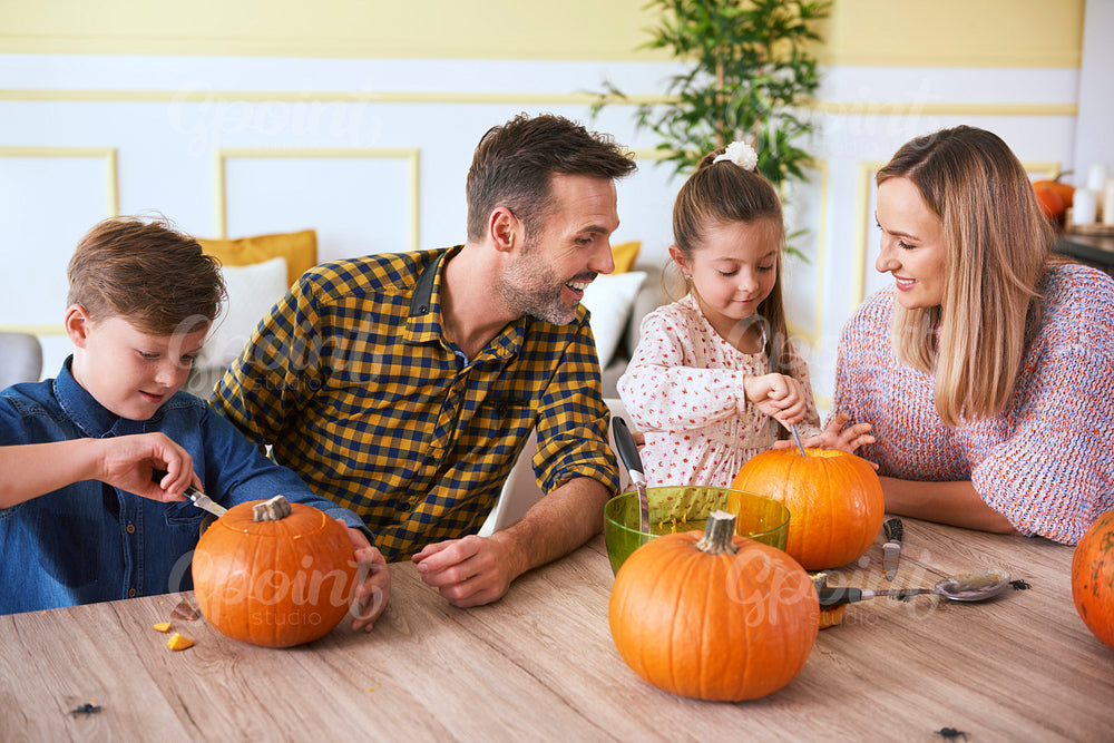 Children carving pumpkins with parents
