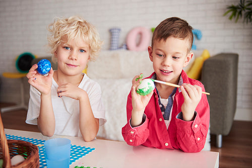 Two happy boys painting eggs for easter time