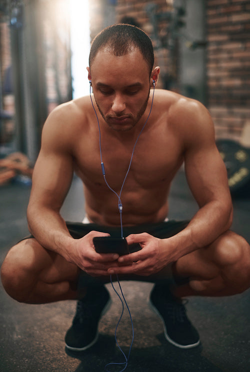 Man listening to music on cell phone at gym