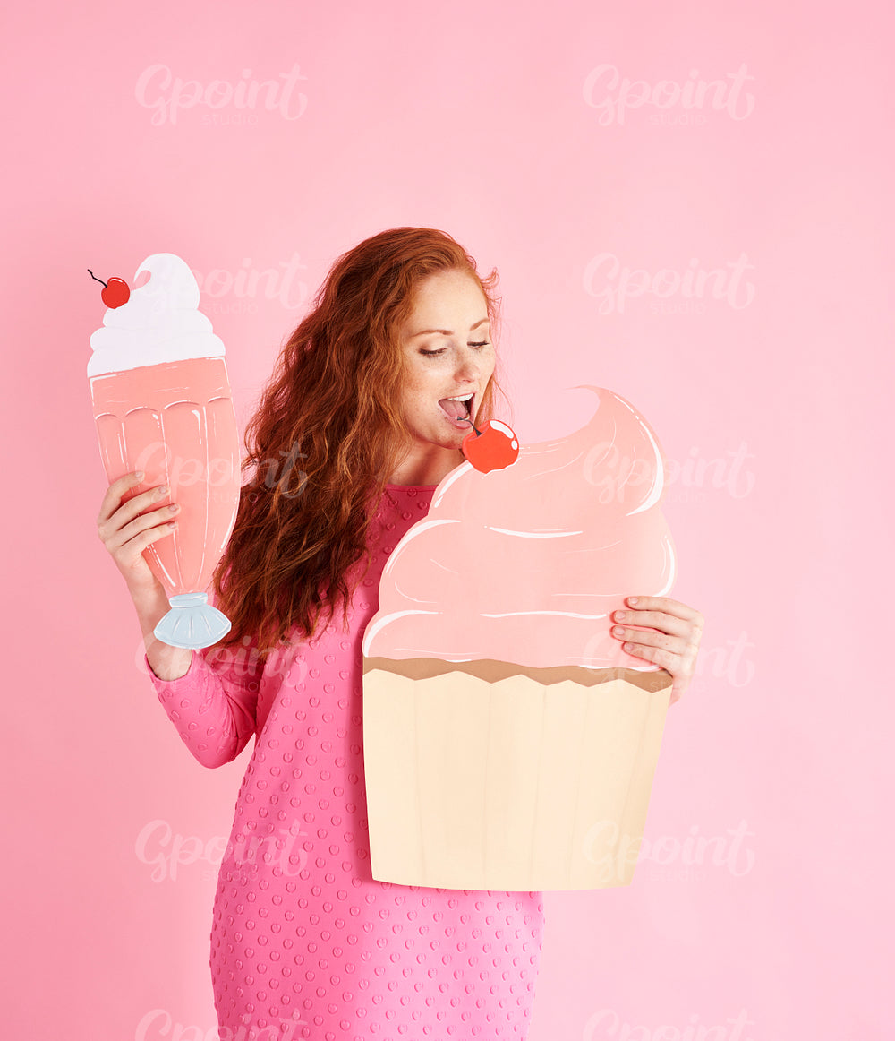Young woman eating a cupcake at studio shot