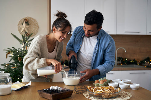 Multi ethnicity couple making a cake together in Christmas time