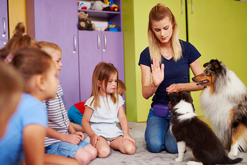Female therapist and her dog playing with children in the preschool
