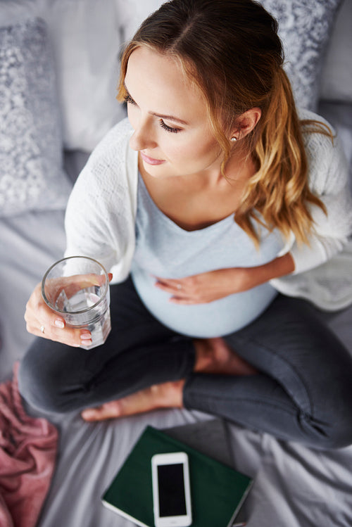 Worried pregnant woman drinking water