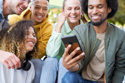 Close up of group of happy people sitting with phone