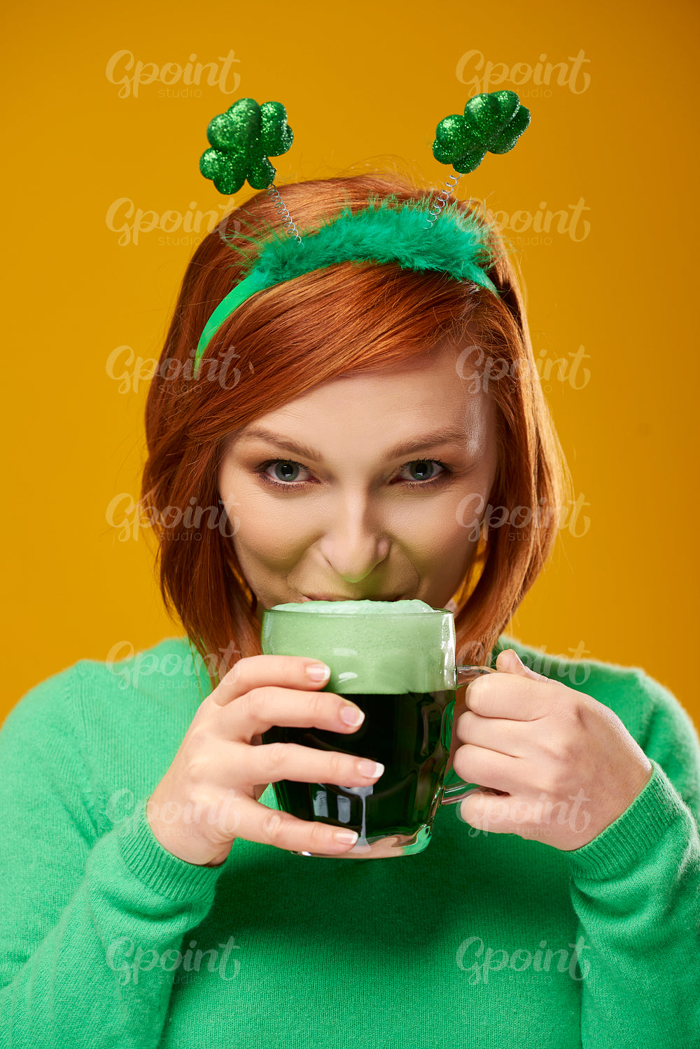 Smiling woman drinking beer in studio shot
