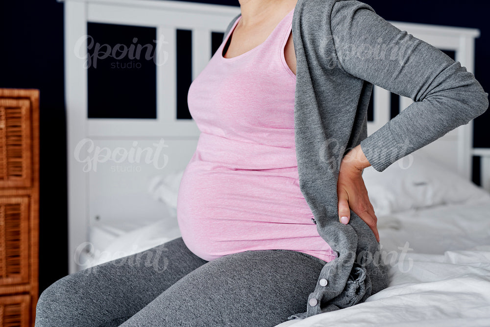 Unrecognizable pregnant woman feeling pain in the back