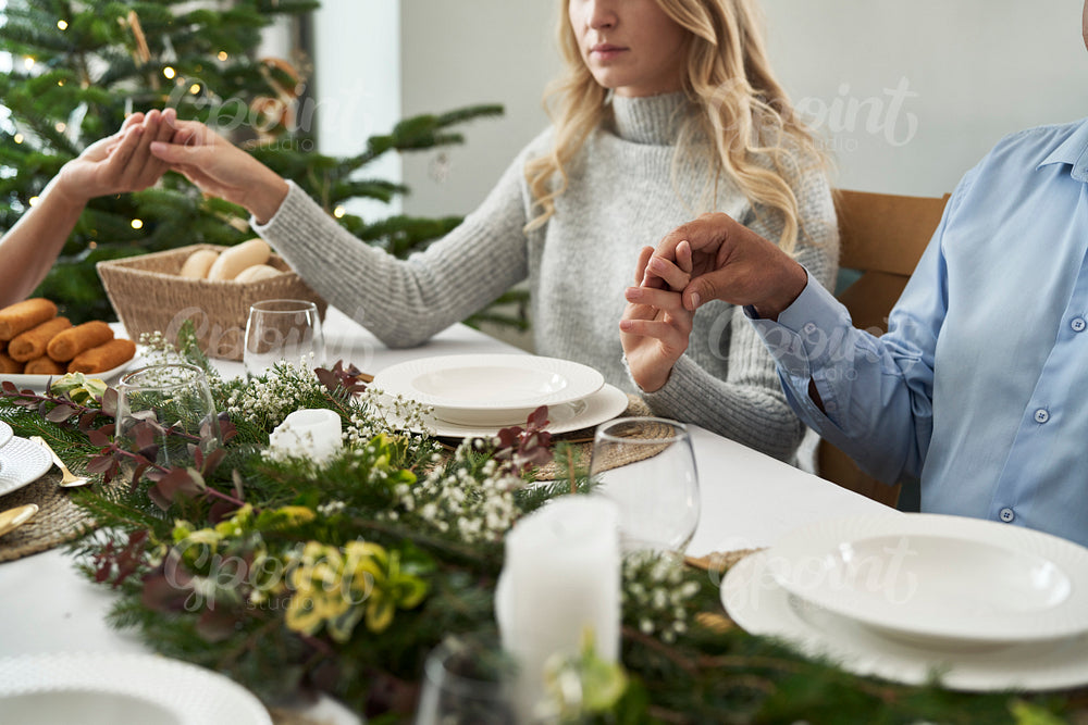 Caucasian family sitting around the table, holding hands and praying 