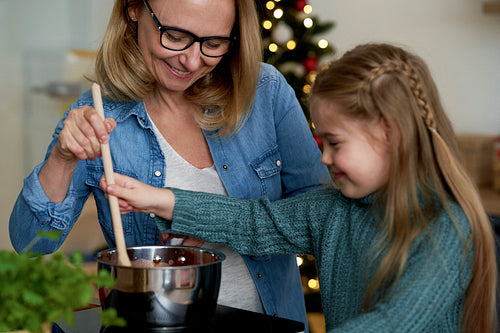 Little girl helping her grandmother in the kitchen during Christmas