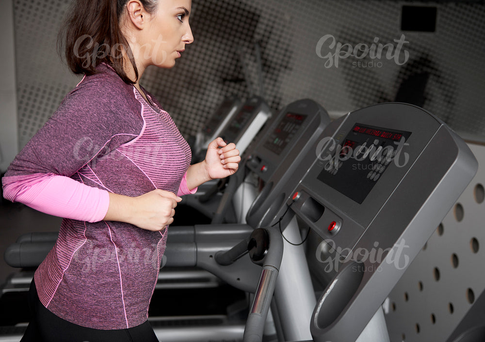 Young woman running on the treadmill at gym
