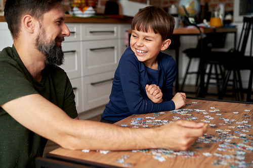 Happy son and father having fun while completing the puzzle