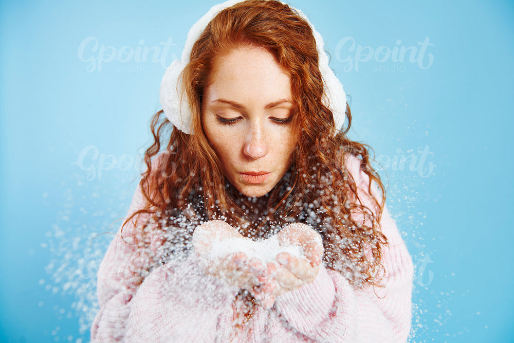 Young woman blowing fake snow at studio shot