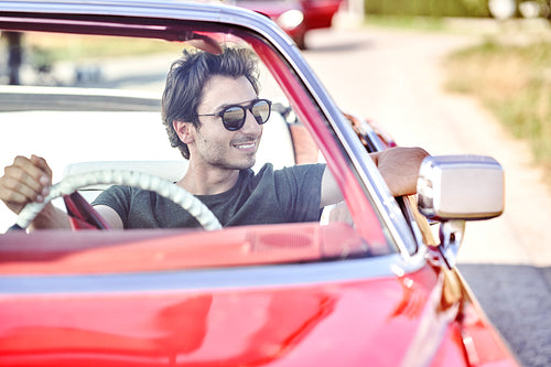 Front view of smiling handsome man in red car