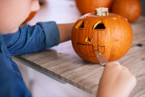Child's hands carving pumpkin for Halloween
