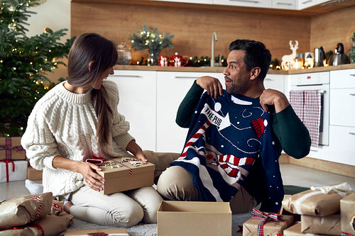 Multi ethnicity couple opening Christmas presents at home