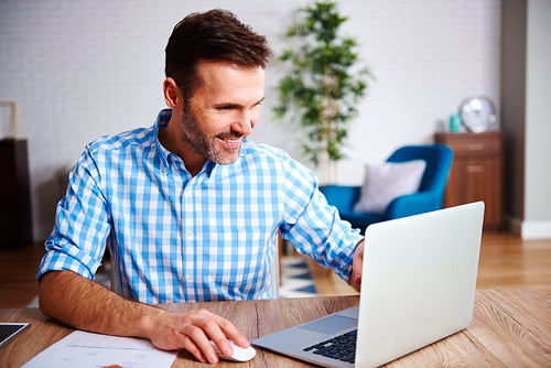 Happy man using laptop in his home office
