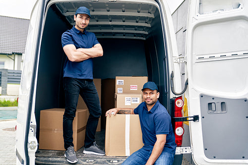 Portrait of couriers in a trunk full of parcels