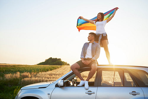 Young couple with rainbow flag enjoying the view