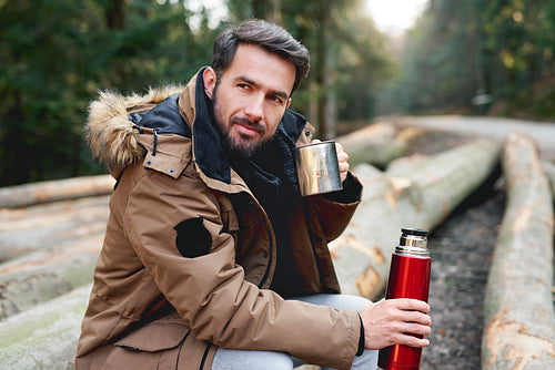 Portrait of handsome man drinking hot tea in autumn forest
