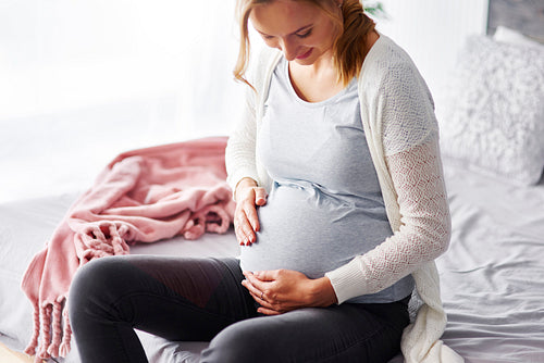 Cheerful pregnant woman touching her stomach