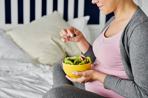 Pregnant woman eating healthy fruity snack