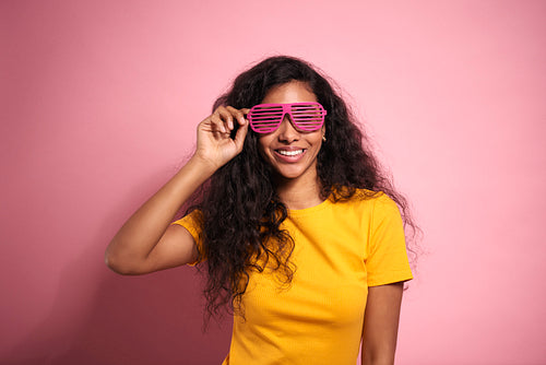 Smiling young African woman in pink eyeglasses in studio shot.