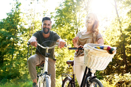 Portrait of happy couple with bicycle in the forest