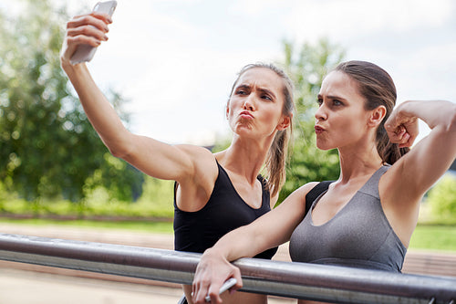 Two athletic strong women making funny faces for selfies
